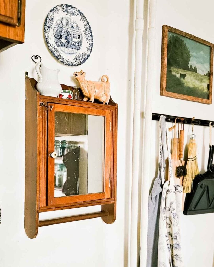 Vintage wood-framed mirrored cabinet styled with an ironstone pitcher and cow creamer, budget kitchen décor.