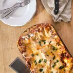 Featured image of baked homemade turkey lasagna in a glass baking dish garnished with parsley.