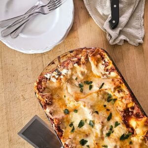 Featured image of baked homemade turkey lasagna in a glass baking dish garnished with parsley.
