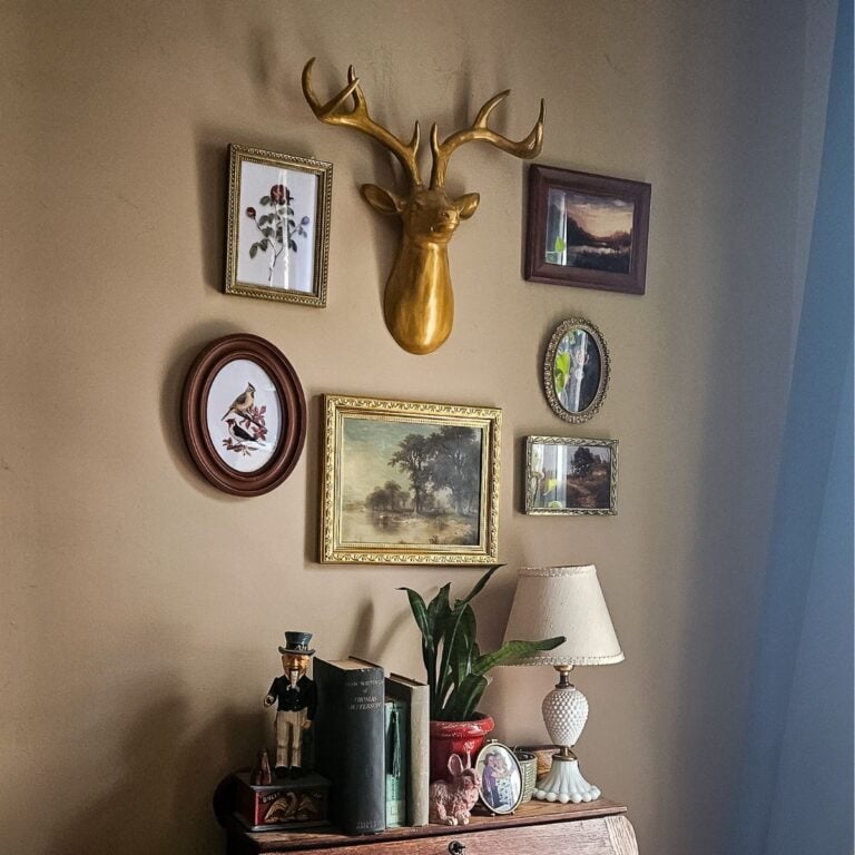 How to create a vintage wall gallery on a budget — finished gallery wall with gold deer head and thrifted frames above an antique desk.