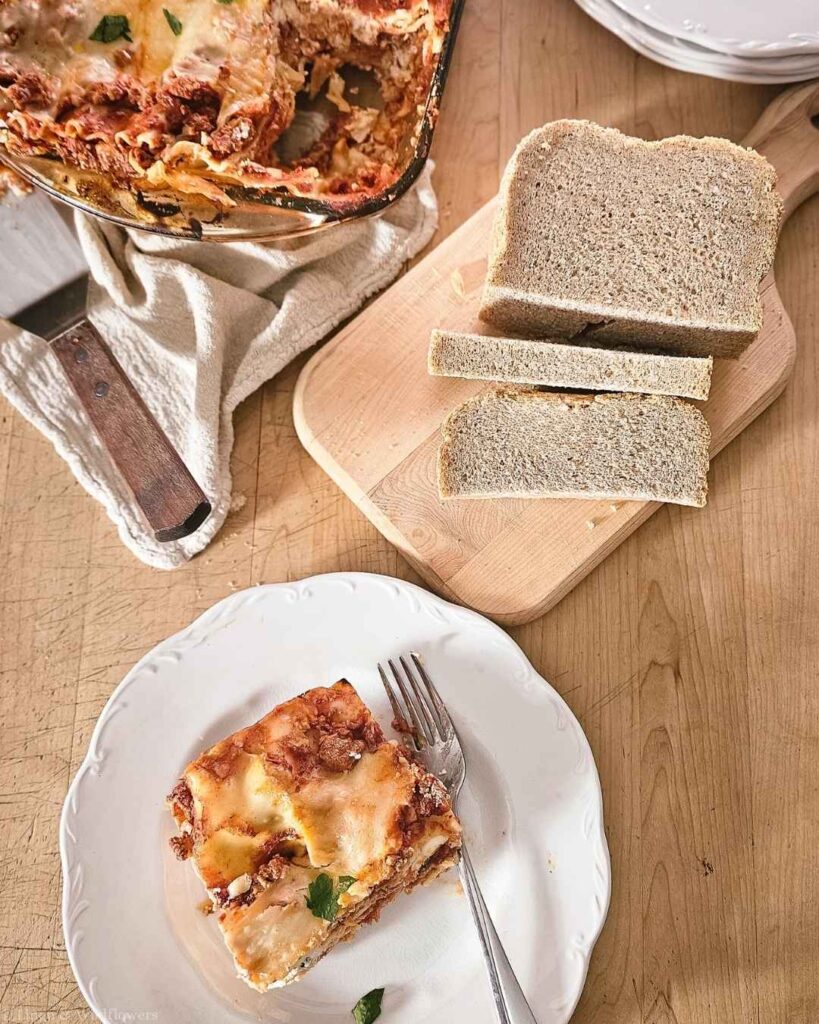 Plated slice of homemade turkey lasagna served with slices of bread.