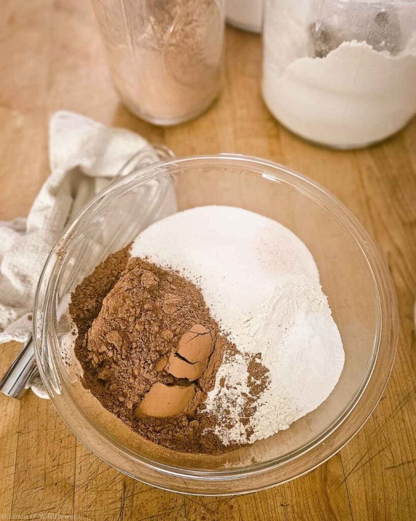Cocoa powder, flour, and sugar in a glass bowl before mixing homemade chocolate cake mix.