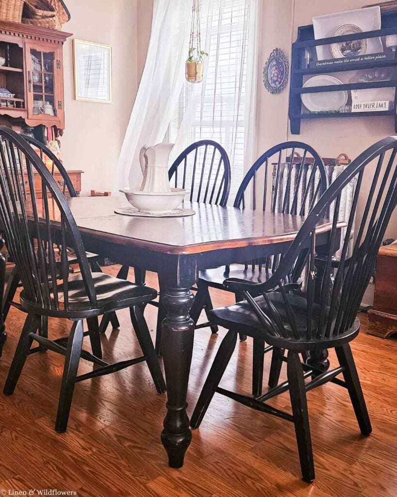 Country style dining room with black Windsor chairs, ironstone pitcher and bowl centerpiece.