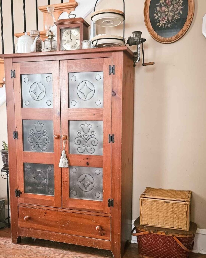 Vintage pie safe pantry cabinet paired with wicker baskets for cozy farmhouse storage.