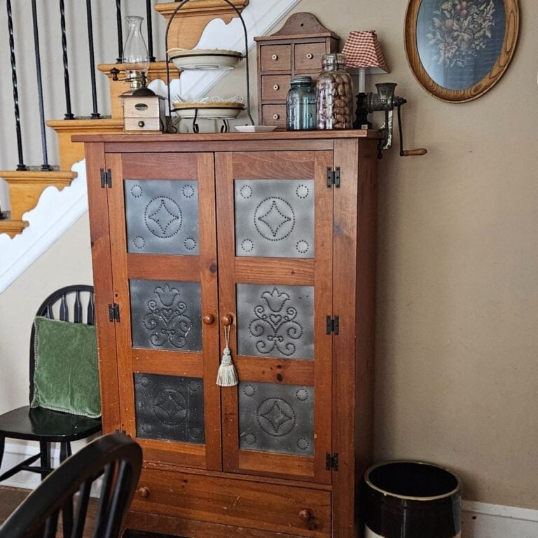 Vintage punched tin pie safe styled with a clock, oil lamp, and ironstone teapot — great pantry storage.