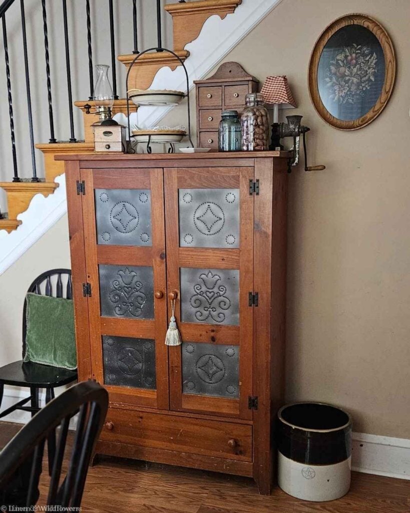 Close-up of punched tin door panels on an antique pie safe with pierced diamond pattern.