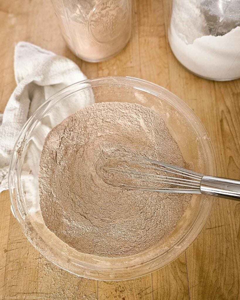 Whisking dry ingredients in a glass bowl to make homemade chocolate cake mix.