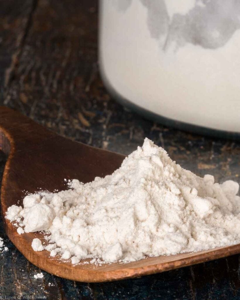 Pile of baking soda on a wooden spoon, a natural cleaning hack for scrubbing and deodorizing around the house.