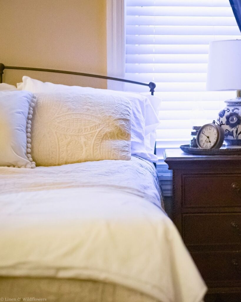 Close-up of layered white bedding and quilted pillows showing how a mattress protector pad stays hidden.