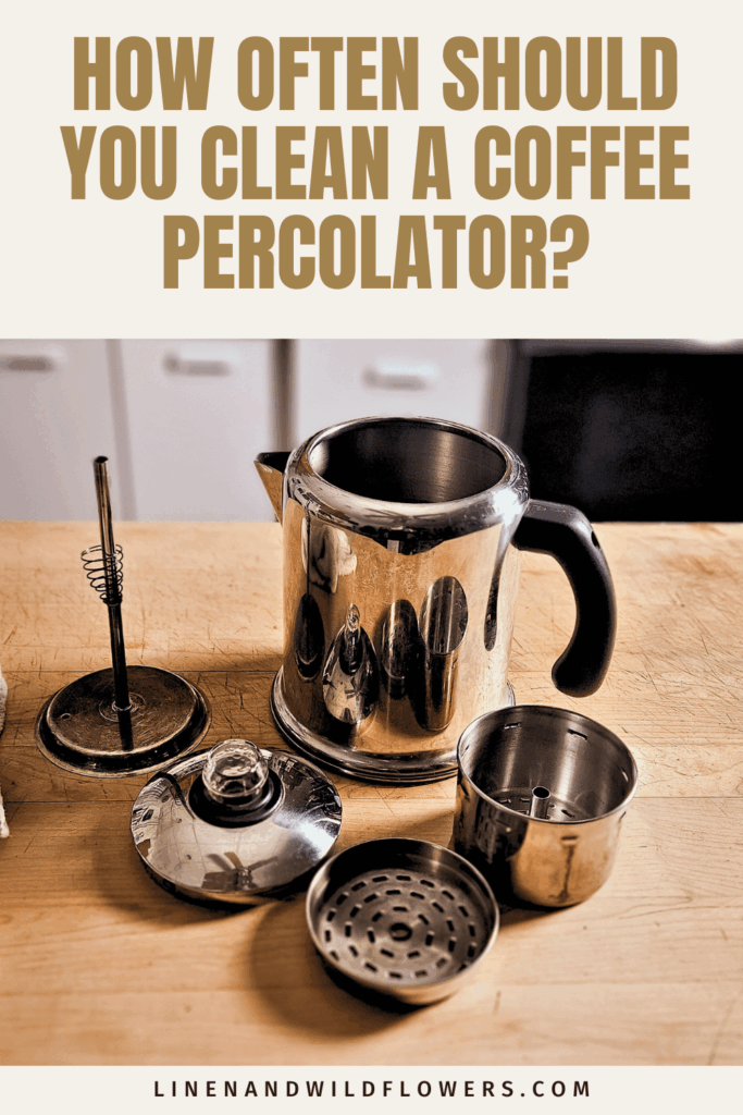 Disassembled stainless steel stovetop coffee percolator with the lid, stem, and filter basket arranged on a wooden kitchen countertop.