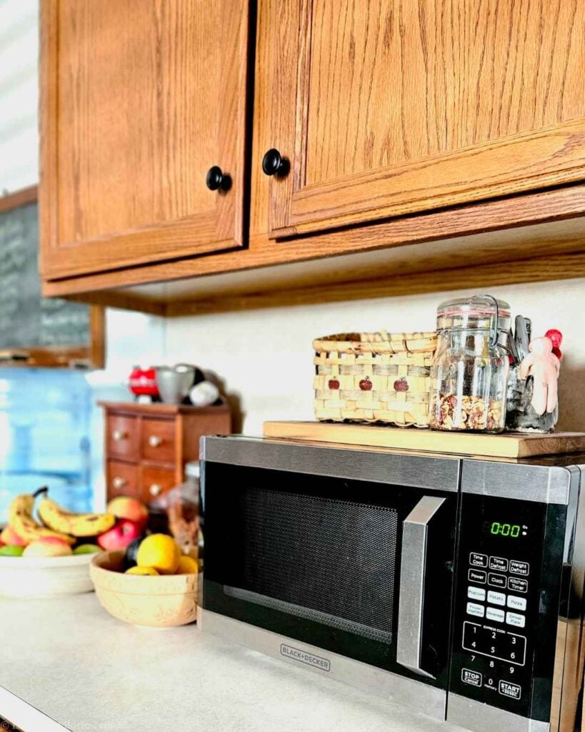 Black+Decker microwave on a kitchen counter under oak cabinets, ready for a quick and easy microwave cleaning hack.