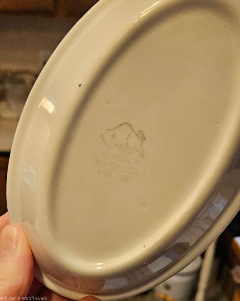 Underside of a white plate showing a buffalo logo and a Buffalo by Oneida USA maker's mark.