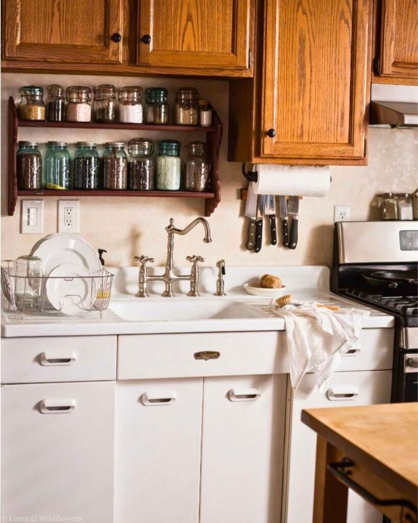 Vintage farmhouse kitchen with white metal cabinets, drainboard sink, oak upper cabinets and a butcher block island.
