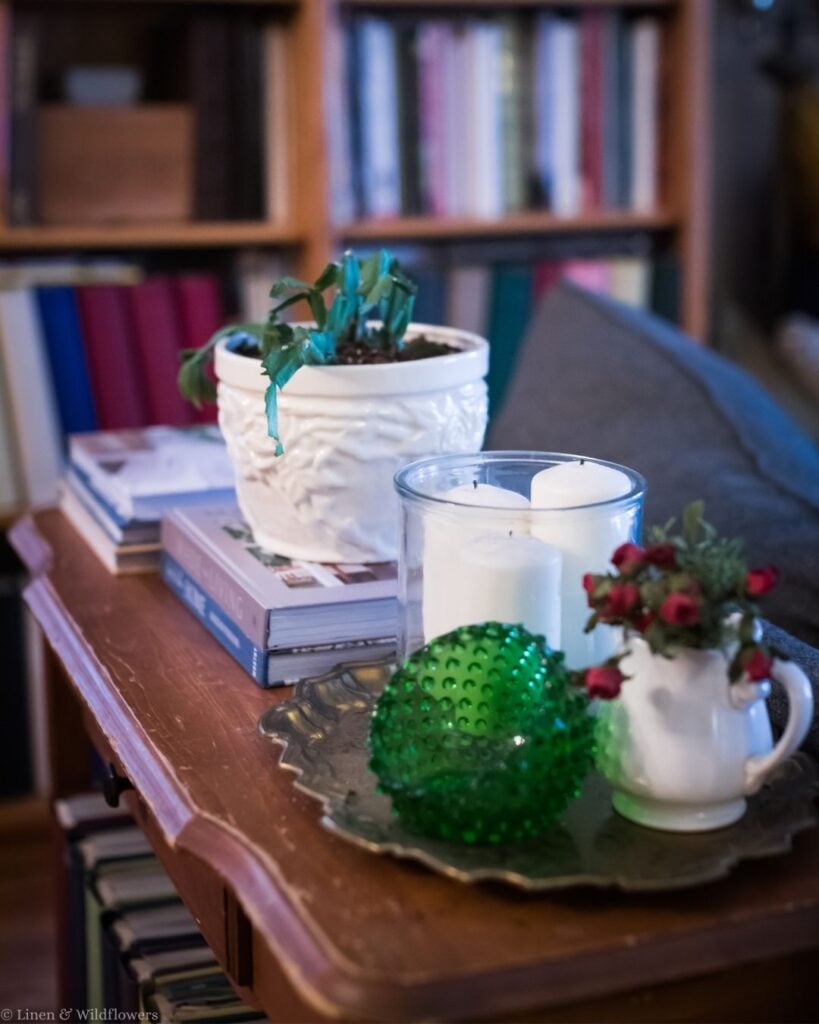 Vintage side table vignette with green hobnail glass, an ironstone pitcher of red roses, and a pewter tray